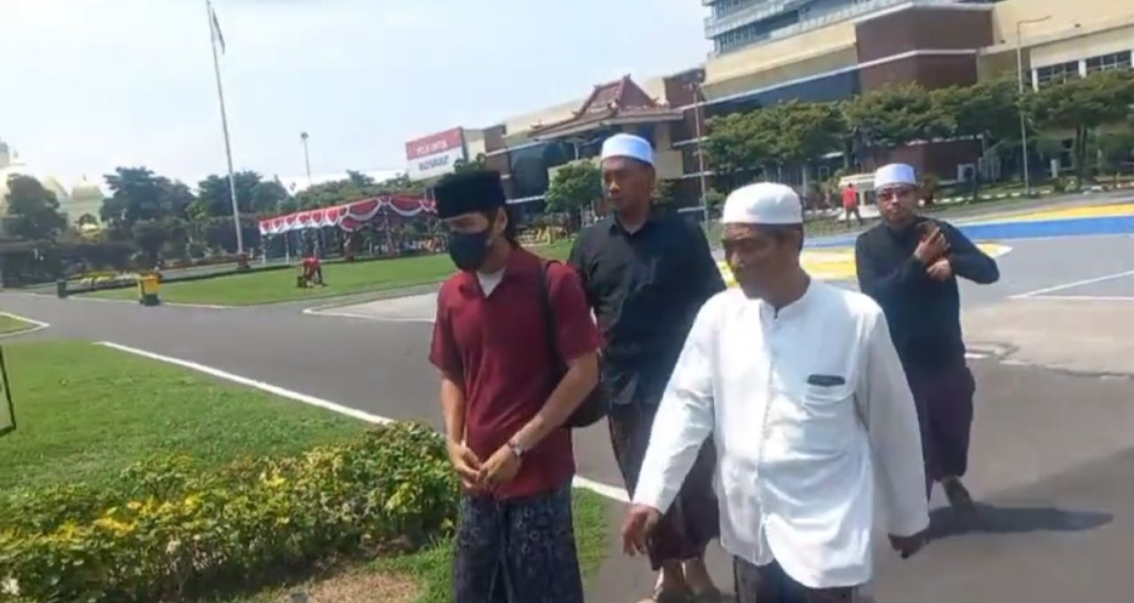 Terduga pelaku berinisil U (baju merah) berjalan menuju gedung Ditreskrimum Polda Jatim