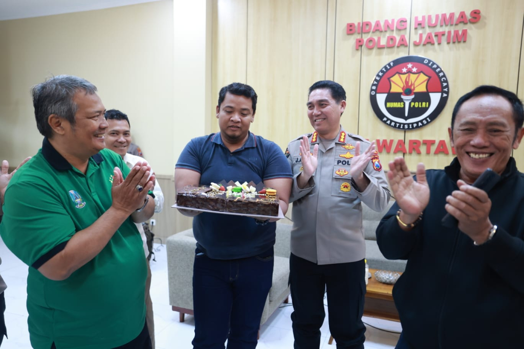Kabidhumas Polda Jatim Kombespol Jules Abraham Abast menyerahkan kue kepada wartawan senior.