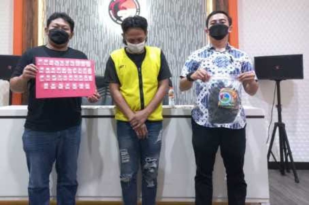 KZ saat diapit oleh petugas di Mapolrestabes Surabaya.